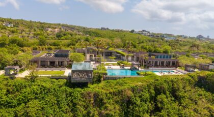 Aerial view of a luxurious villa with an infinity pool on a cliffside in Bali, Indonesia.