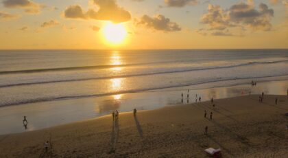 Beautiful sunset on Seminyak Beach, Bali with people enjoying the view and golden sands.