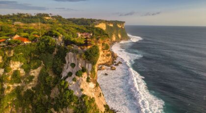 A breathtaking view of Uluwatu's coastal cliffs in Bali during a golden sunset, showcasing nature's beauty.